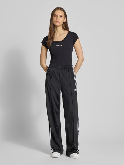 Frauenmodel trägt Cropped T-Shirt mit Label-Print von adidas Sportswear in Schwarz, Slim Fit, Material-Mix mit Stretch-Anteil, gerippter Rundhalsausschnitt, Ganzkörperansicht von vorne. Rückenlänge bei Größe S: 49 cm.