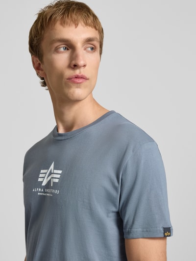 Mannelijk model draagt T-Shirt met Logo en ronde hals van Alpha Industries, lichtblauw katoen, regular fit, logoprint, detailopname bovenlichaam.