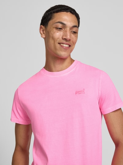 Männermodel trägt T-Shirt mit Rundhalsausschnitt und Label-Stitching von Superdry in Pink aus Reine Baumwolle, Slim-Fit, Nahaufnahme Oberkörper.