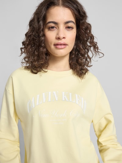 Frauenmodel trägt Sweatshirt mit Label-Print Modell 'GRAPHIC' von Calvin Klein Jeans in Pastellgelb, Baumwoll-Elasthan, Nahaufnahme Oberkörper.