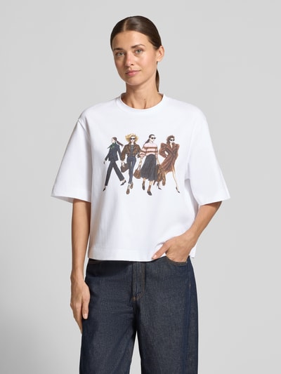 Frauenmodel trägt Relaxed Fit T-Shirt aus reiner Baumwolle von Rich & Royal, weiß mit Motiv-Print und Strasssteinbesatz, Ganzkörperansicht von vorne