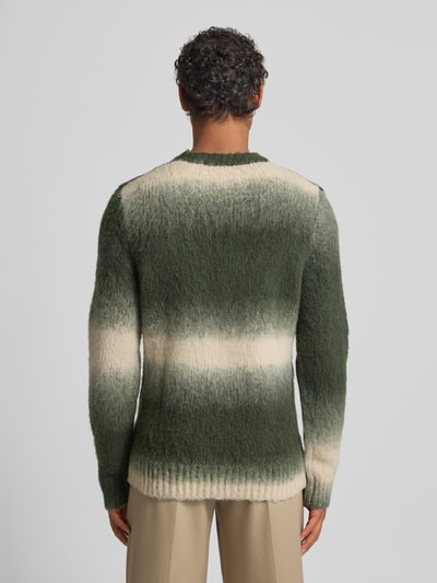 Männermodel trägt Strickpullover mit gerippten Abschlüssen Modell 'FABIO' von Samsøe Samsøe, grün-weiß melierter Woll-Mix, Ganzkörperansicht Rückansicht.