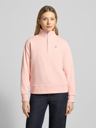 Frauenmodel trägt Sweatshirt mit Baumwoll-Anteil von Gant in zartem Rosa, lockerer Schnitt, Troyer-Kragen, Label-Stitching, gerippte Abschlüsse, Baumwoll-Mix, Ganzkörperansicht von vorne.