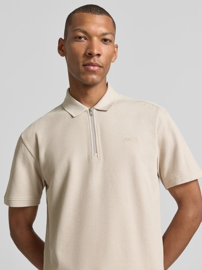 Männermodel trägt Regular Fit Poloshirt aus reiner Baumwolle Modell 'Pe_RibNylon' von BOSS Orange, beige Farbe, feine Rippstruktur, Nahaufnahme Oberkörper. Herren Poloshirt von BOSS Orange.