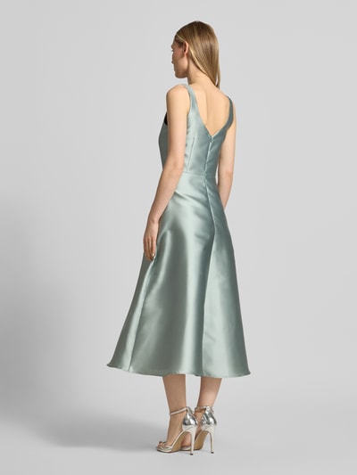 Frauenmodel trägt Cocktailkleid mit Karree-Ausschnitt von Swing, Midikleid aus glänzendem Stoff in Mint, Rückenreißverschluss, taillierte Passform, Rückenlänge 125 cm, Brustweite 34 cm, Ganzkörperansicht Rückansicht.