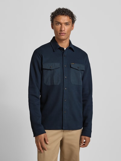 Männermodel trägt Regular Fit Hemdjacke mit Brusttaschen von PME Legend, Baumwoll-Mix mit Stretch-Anteil, Strukturmuster, Kentkragen, Knopfleiste, Label-Details, Rückenlänge 74 cm, dunkelblaue Farbe, Ganzkörperansicht von vorne.