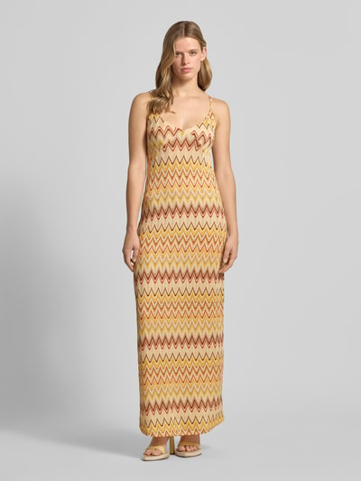Vrouwenmodel draagt Maxikleid im Allover-Look van Gina Tricot, materiaalmix met stretch, recht model, V-hals, spaghettibandjes, all-over look, lichtgeel en bruin zigzagpatroon, ruglengte maat S 150 cm, borstwijdte 32 cm. Ganzkörperaanzicht van voren.