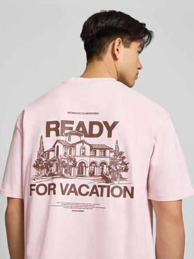 Männermodel trägt Oversized T-Shirt mit Label-Detail Modell 'Bovec' von Pegador in Rosa, Baumwolle, Rücken-Print, Oversized-Fit, Ganzkörperansicht Rückansicht. Herren T-Shirt, Rundhalsausschnitt, Rückenlänge bei Größe M 71 cm.