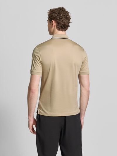 Männermodel trägt Slim Fit Poloshirt aus reiner Baumwolle Modell 'PENROSE 38' von BOSS, beige mit Kontraststreifen, Ganzkörperansicht Rückansicht.