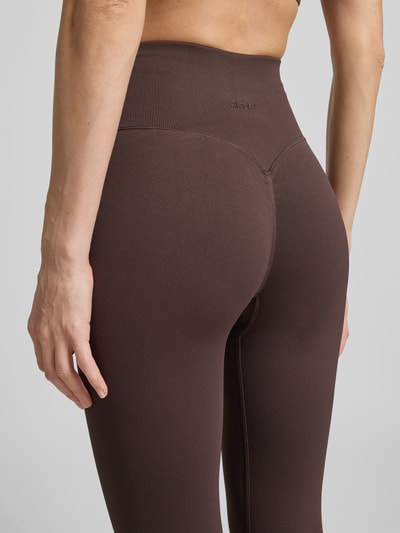 Frauenmodel trägt Leggings mit Logo von aim'n aus Material-Mix mit Stretch-Anteil, körpernahe Passform, elastischer Bund, Nahaufnahme Rückansicht.
