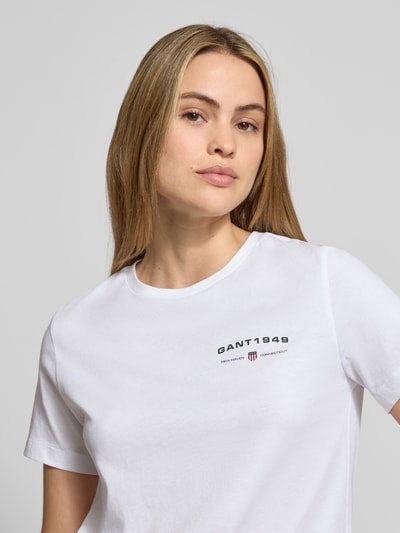 Modelka kobieca nosi T-Shirt mit Label-Print und Rundhalsausschnitt od Gant, biała bawełna, regular fit, ujęcie zbliżeniowe górnej części ciała.