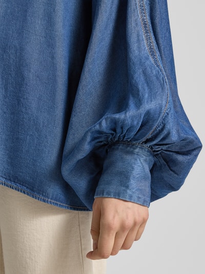 Kobieta nosi Oversized Jeansbluse aus Lyocell Modell 'C_BETTA' od BOSS Orange, denim, krój oversized, rękawy nietoperzowe, mankiet, materiał lyocell, detal rękawa, zbliżenie