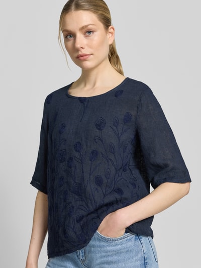 Vrouwenmodel draagt Blusenshirt met Stitchings model 'No44raa' van ZABAIONE, relaxed fit, ronde hals, 1/2-mouwen, ruglengte maat S 66 cm, mouwlengte maat S 30 cm, donkermarineblauw met geborduurd bloemenmotief, textuur van linnen, geheelbeeld van voren.
