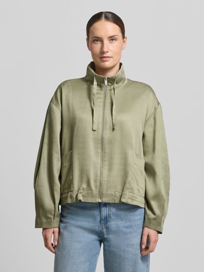 Frauenmodel trägt Jacke aus Lyocell-Baumwoll-Mix Modell 'Jarusa' von OPUS in grün, Relaxed Fit, Stehkragen, Reißverschluss, Ganzkörperansicht von vorne.