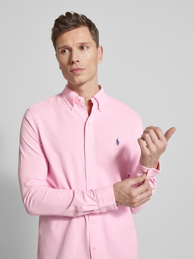 Mannmodel draagt Regular Fit Freizeithemd aus reiner Baumwolle van Polo Ralph Lauren in effen roze, piqué katoen, lange mouw, logo-stitching, button-down kraag; Nahaufnahme bovenlichaam, voorkant.