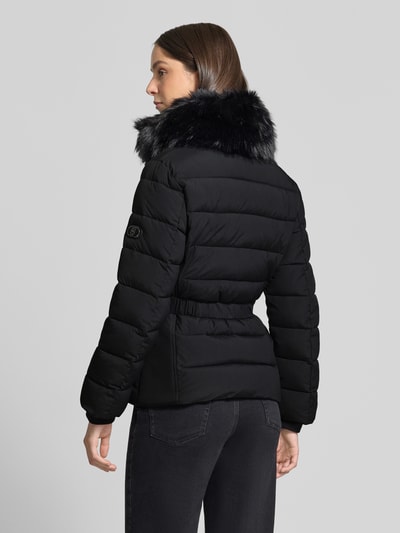 Frauenmodel trägt Jacke mit Kunstfellbesatz Modell 'IMBOTTITO' von Liu Jo, schwarze Farbe, Ziersteinbesatz, taillierte Passform, Ganzkörperansicht Rückansicht.