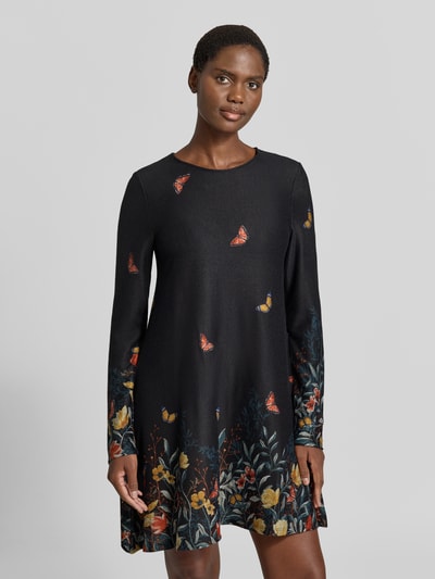 Frauenmodel trägt Minikleid mit Rundhalsausschnitt von Apricot, dunkle Grundfarbe mit floralen und Schmetterlingsmotiven, Material-Mix mit Stretch-Anteil, A-Linie, Ganzkörperansicht von vorne.