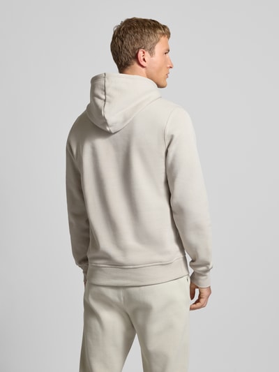 Männermodel trägt Hoodie mit Kapuze von CHAMPION in Beige, Baumwoll-Mix, Lockerer-Schnitt, gerippte-Abschlüsse, Rückenlänge 70 cm, Ganzkörperansicht Rückansicht.