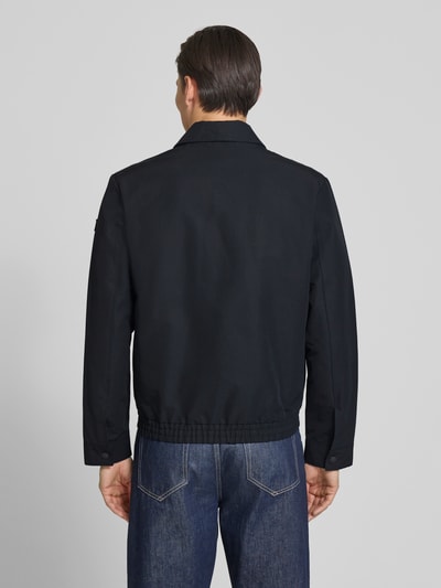 Männermodel trägt Regular Fit Blouson mit elastischem Bund von Marc O'Polo, look: effen, regular fit pasvorm, platte kraag, ritssluiting, labelpatch, lange mouw met drukknoop, elastische rompzoom, zij-steekzakken, binnenzak, kleur donkerblauw, textuur glad, ganzkörperansicht rückansicht.