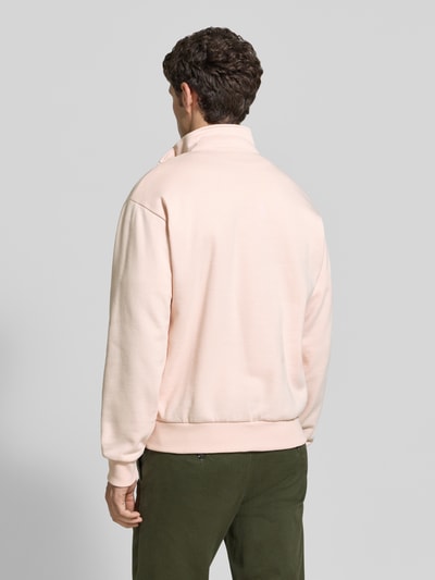 Männermodel trägt Regular Fit Troyer aus Baumwoll-Mix von Lacoste in zartem Rosa mit glatter Textur, Ganzkörperansicht Rückansicht. Herren Troyer von Lacoste