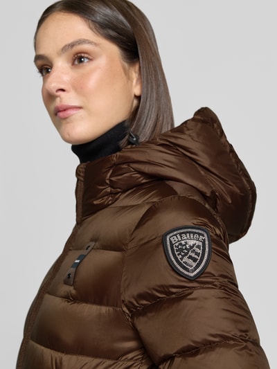 Frauenmodel trägt Mantel in Stepp-Optik Modell 'Agnes' von Blauer USA in Braun, Kapuze, Logo-Detail, Nahaufnahme Oberkörper.