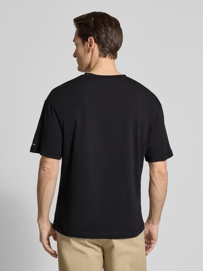 Männermodel trägt Regular Fit T-Shirt aus reiner Baumwolle von Tommy Hilfiger, unifarbenes Jersey, Rundhals, Label Print, Ganzkörperansicht Rückansicht.