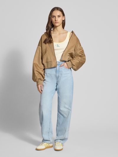 Frauenmodel trägt Trägertop in Ripp-Optik mit Logo von Calvin Klein Jeans in Beige, schlichter Schnitt, Slim Fit, Nahaufnahme Oberkörper.