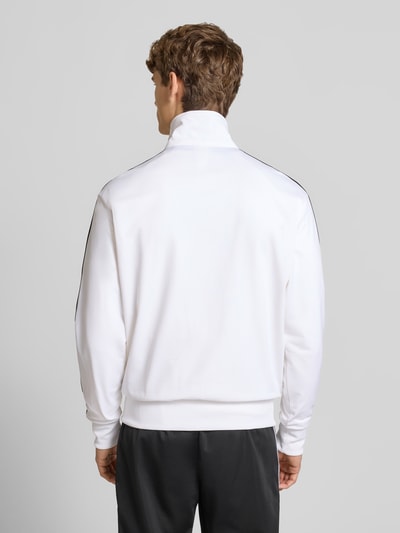 Männermodel trägt Trainingsjacke mit Stehkragen von adidas Originals in Weiß mit Reißverschluss und Label-Stitching, Ganzkörperansicht Rückansicht.