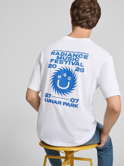 Männermodel trägt Regular Fit T-Shirt aus reiner Baumwolle Modell 'Nunarix' von HUGO, Optik: Unifarben, Label-Print auf Rücken, Materialverarbeitung: Jersey, Farbe: Weiß und Blau, Ganzkörperansicht Rückansicht.