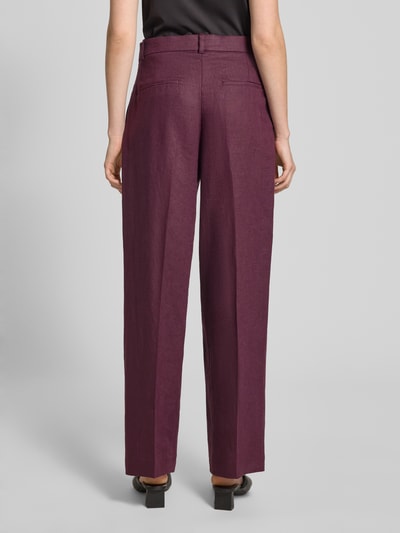 Frauenmodel trägt Straight Fit Leinenhose mit Bügelfalten Modell 'Tempoli' von Mango in Dunkellila, Reine Leinen, Ganzkörperansicht Rückansicht.