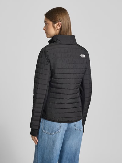 Frauenmodel trägt schwarze, gesteppte Steppjacke mit Logo Modell 'CANYONLANDS' von The North Face, Rückenansicht, Ganzkörperansicht Rückansicht. Slim Fit, Stehkragen, Reißverschlüsse und strukturierte Oberfläche, Kontext: Damen Steppjacke, Größe S Maße.