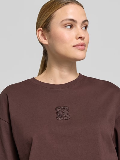 Frauenmodel trägt Cropped Boxy Fit T-Shirt mit Rundhalsausschnitt von Smith and Soul aus reiner Baumwolle mit Stitching in Braun, Nahaufnahme Oberkörper.