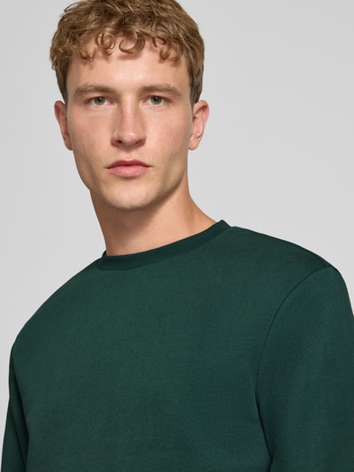 Männermodel trägt Regular Fit Sweatshirt aus Baumwoll-Mix Modell 'CERES' von ONLY in dunklem Grün, Nahaufnahme Oberkörper, Herren Sweatshirt von ONLY & SONS.