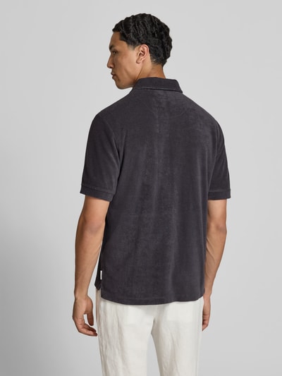 Männermodel trägt Regular Fit Poloshirt aus Baumwoll-Mix von Closed in Schwarz mit Nicki-Oberfläche, Polokragen und Brusttasche, Rückansicht.