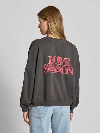 Frauenmodel trägt Oversized Sweatshirt mit Label-Stitching von OH APRIL in Dunkelgrau aus reiner Baumwolle mit Rundhalsausschnitt, Ganzkörperansicht Rückansicht.
