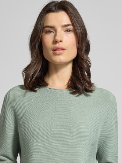 Frauenmodel trägt Strickpullover mit Rundhalsausschnitt von Comma aus Baumwoll-Mix, Regular-Fit, Rollsaum, Nahaufnahme Oberkörper.