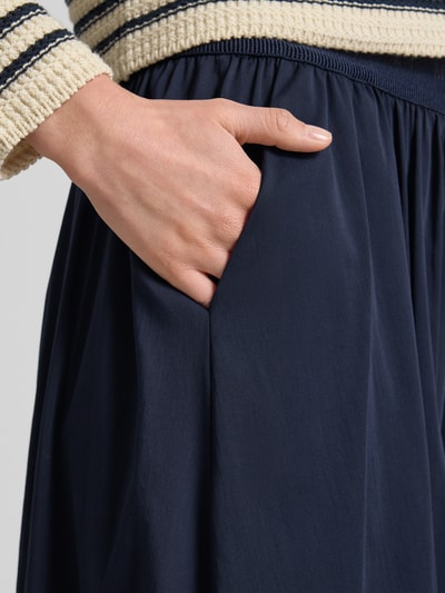 Kobieta nosi spódnica midi z mieszanki bawełny z dodatkiem streczu, linia a, model 'SNOS' od Milano Italy, detal z logo, detal: elastyczny pas, kolor granatowy, gładka struktura, detal: kieszeń, zbliżenie biodra, detailaufnahme