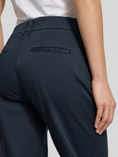 Kobiece model prezentuje Straight Fit Stoffhose mit Lyocell-Anteil Modell 'Mara' od Brax, ciemny niebieski, gładka struktura, zbliżenie na tył. Szerokość w rozmiarze 36: 39 cm, długość nogawki: 68 cm, bawełniana mieszanka z lyocellem, proste nogawki, kieszenie, zapięcie na guzik i zamek.