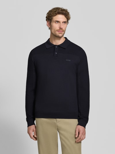 Männermodel trägt Relaxed Fit Poloshirt mit Woll-Anteil Modell 'KN_Momentum-X PL' von BOSS Green in Dunkelblau, Ganzkörperansicht von vorne.