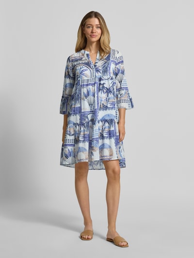 Frauenmodel trägt Tunikakleid im Allover-Look mit V-Ausschnitt von Emily Van den Bergh, blau-weiß gemustert, reine Baumwolle, A-Linie, Minikleid, Trompetenärmel, Ganzkörperansicht von vorne.