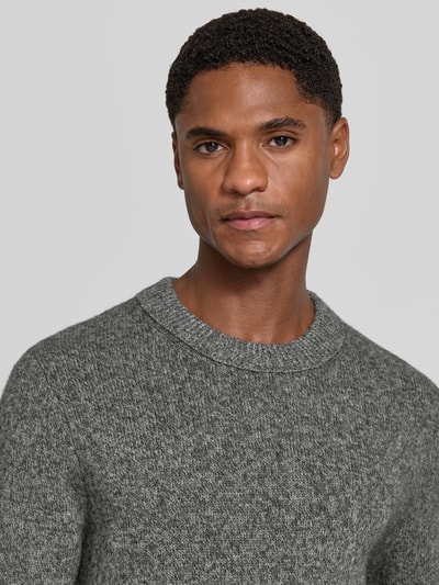 Männermodel trägt Wollpullover aus reiner Wolle Modell 'Harlow' von Tiger of Sweden, grauer Mix von wol en jak, recht model, ronde hals, ribboorden, Nahaufnahme Oberkörper.
