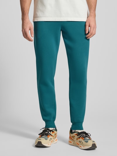 Männermodel trägt Sweatpants mit elastischem Bund von PUMA PERFORMANCE aus Baumwoll-Mix, Türkis, Label-Stitching, Nahaufnahme Unterkörper.