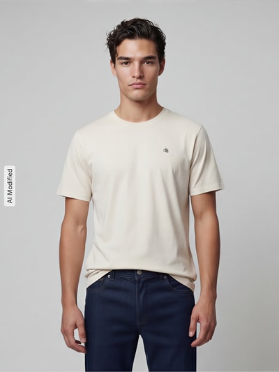Männermodel trägt T-Shirt mit Label-Stitching und Rundhalsausschnitt von Scotch & Soda in Beige, reine Baumwolle, Regular Fit, Ganzkörperansicht von vorne.