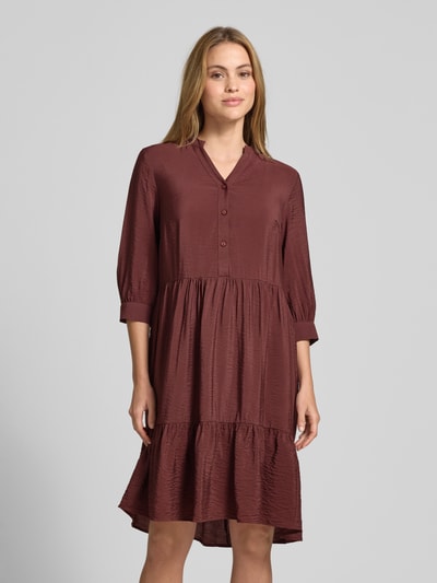 Frauenmodel trägt Relaxed Fit Midikleid aus Viskose-Mix mit Tunika-Ausschnitt und Knopfleiste von Christian Berg Woman in Braun, Ganzkörperansicht von vorne. Rückenlänge bei Größe 36: 106 cm, Brustweite bei Größe 36: 45 cm, Ärmellänge bei Größe 36: 44 cm, Halbarm, strukturierte Oberfläche.