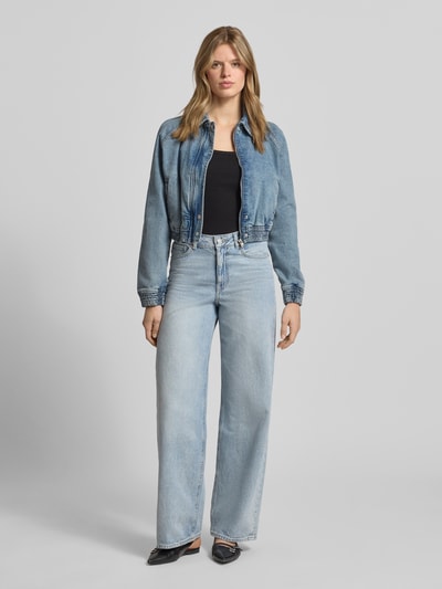 Frauenmodel trägt Relaxed Fit Jeans-Bomberjacke aus Baumwoll-Mix von Hugo Blue in Denim-Optik mit Umlegekragen und verdecktem Reißverschluss, Ganzkörperansicht von vorne.