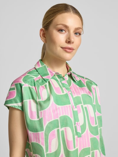 Modelka nosi Regular Fit Bluse im Allover-Look od Milano Italy w zielono-różowy wzór, czysta bawełna, krój regular fit, kołnierzyk koszulowy, listwa guzikowa, rękaw typu cap, długość tyłu w rozmiarze 36: 68 cm, zbliżenie na górną część ciała.