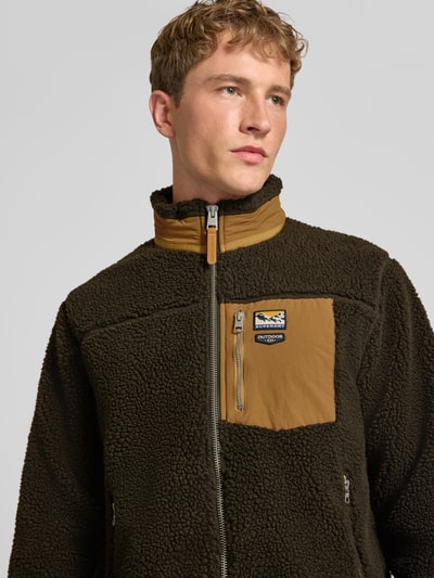 Männermodel trägt Fleecejacke mit Label-Details Modell 'MOUNTAIN' von Superdry, Teddyfell, Reißverschluss, Nahaufnahme Oberkörper.