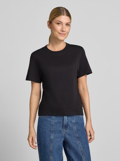 Frauenmodel trägt Regular Fit T-Shirt aus reiner Baumwolle von s.Oliver RED LABEL in Schwarz, kombiniert mit blauer Jeans, Nahaufnahme Oberkörper.