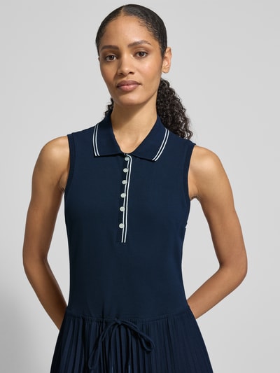 Modelka nosi Tailliertes Freizeitkleid aus Baumwoll-Mix od Tommy Hilfiger, kolor granatowy, plisowany dół, bawełniany, krój slim fit, zapięcie na guziki, kołnierzyk polo, szerokie ramiączka, widok na górną część ciała z przodu.