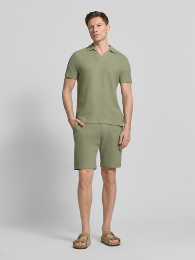 Männermodel trägt Sweatshorts mit elastischem Bund von MCNEAL in Grün mit Strukturmuster, Gerade Passform, Eingriff- und Gesäßtaschen, Elastischer-Material-Mix, Ganzkörperansicht von vorne.